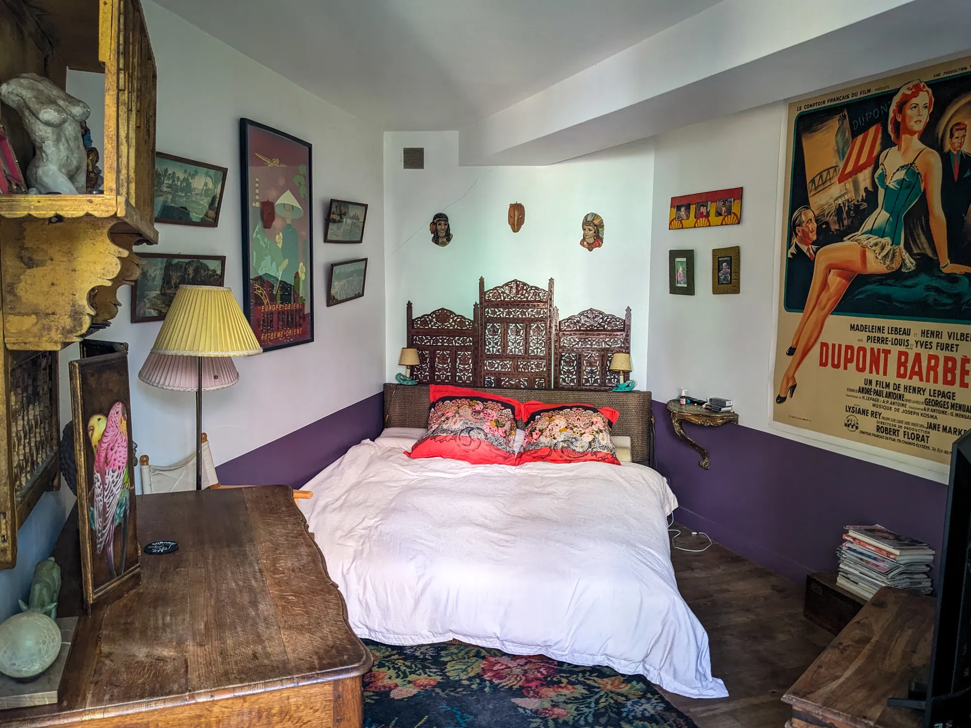 Chambre avec lit sculpté et affiche de cinéma