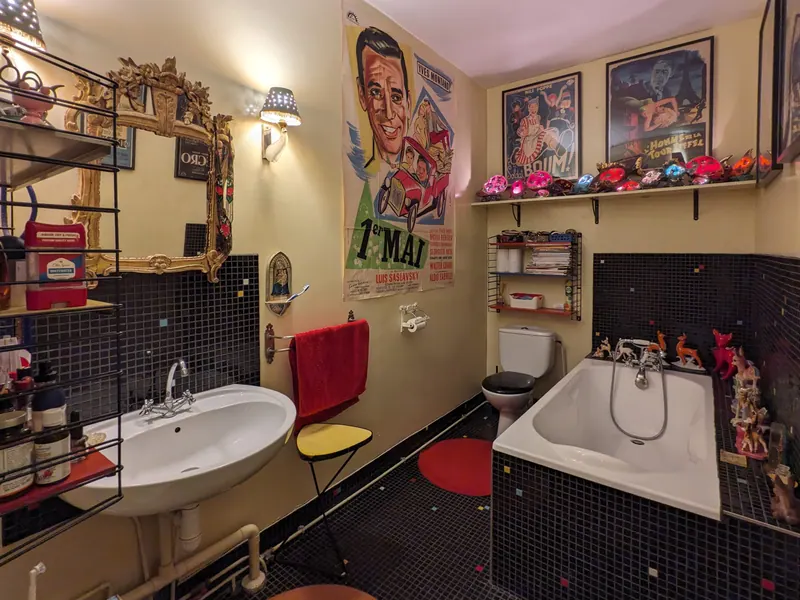 Bathroom with bathtub, black tiles and vintage film posters