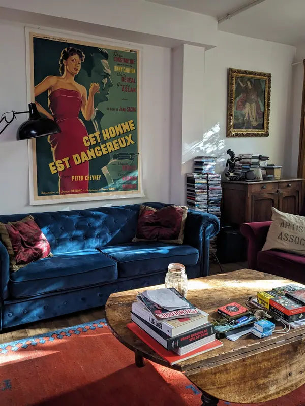 Living room: blue sofa, antique coffee table and film poster